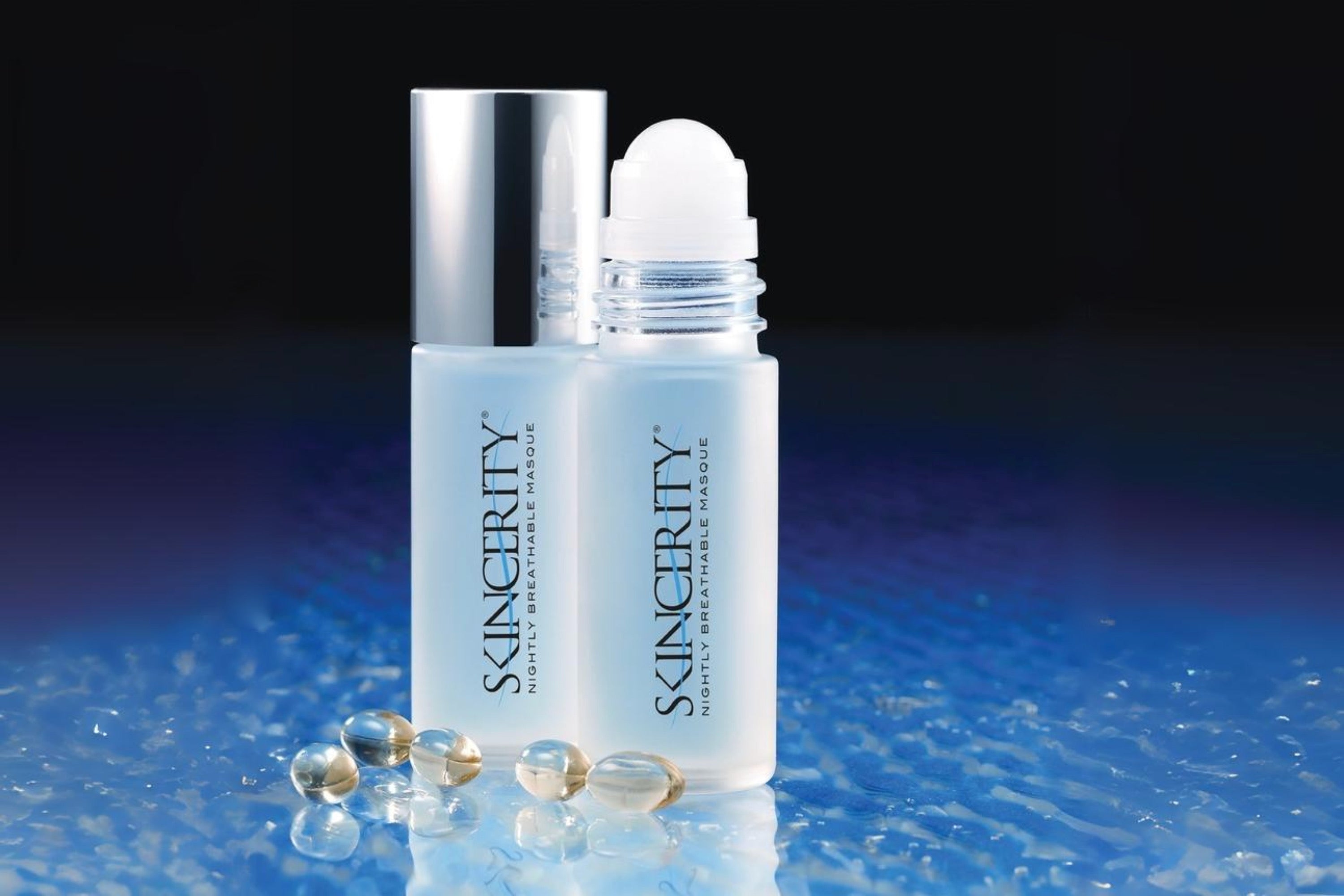 A 2009 image of 2 bottles of Skincerity Nightly Breathable Masque next to capsules of Vitamin E, an active ingredient in Skincerity's breathable barrier technology. One bottle has the cap off to highlight the roll-on applicator.