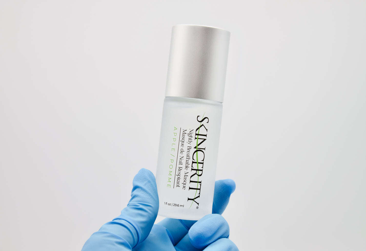 A hand wearing a glove is holding a bottle of Skincerity Apple, emphasizing Skincerity's scientific foundation