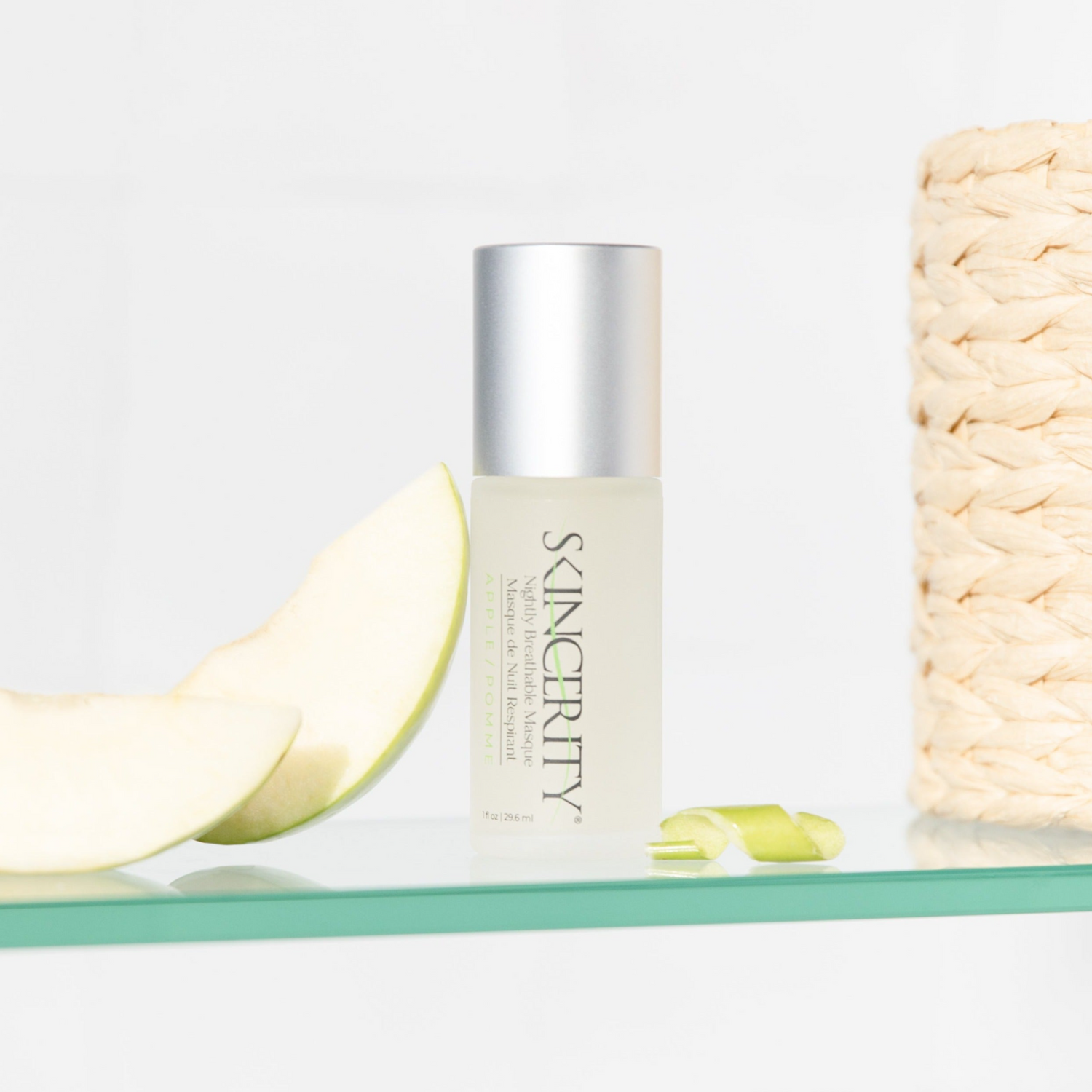 Skincerity bottle displayed on a glass shelf with fresh green apple slices, promoting its fresh apple scent