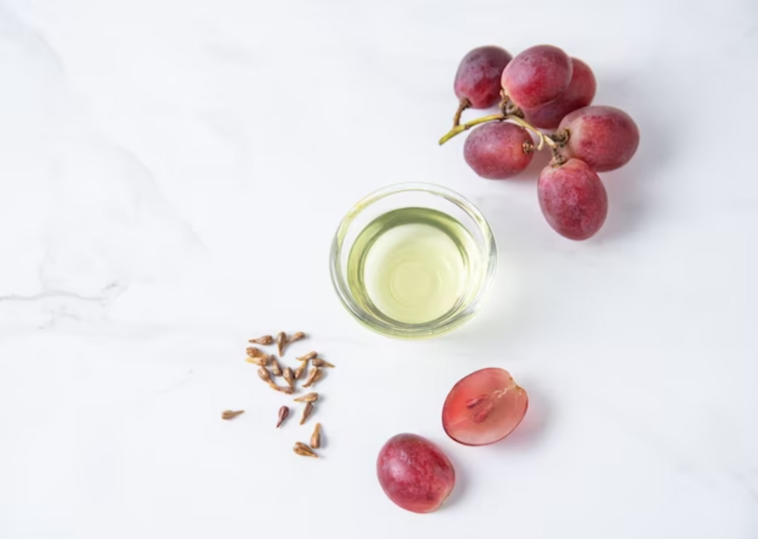 Grape seed oil in a mini glass prep bowl with fresh grapes and seeds, highlighting its antioxidant properties in Skincerity